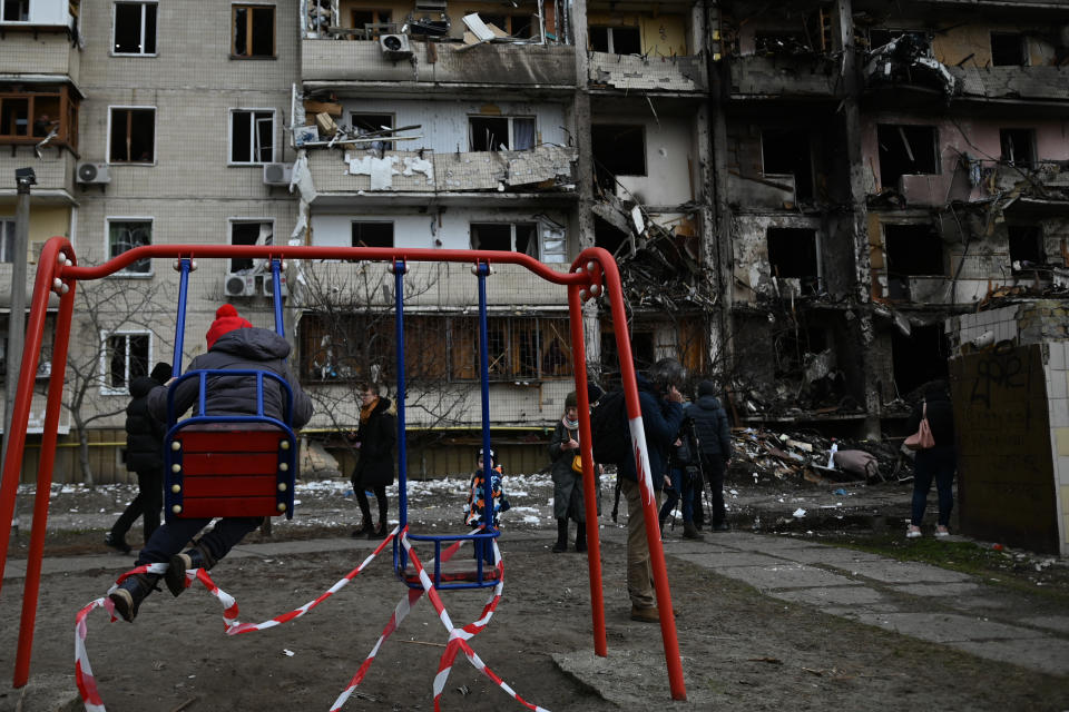 People clean-up the damage at an apartment complex after a rocket attack during Russia's attack on the Ukraine in Kharkivskiy District, Kyiv.