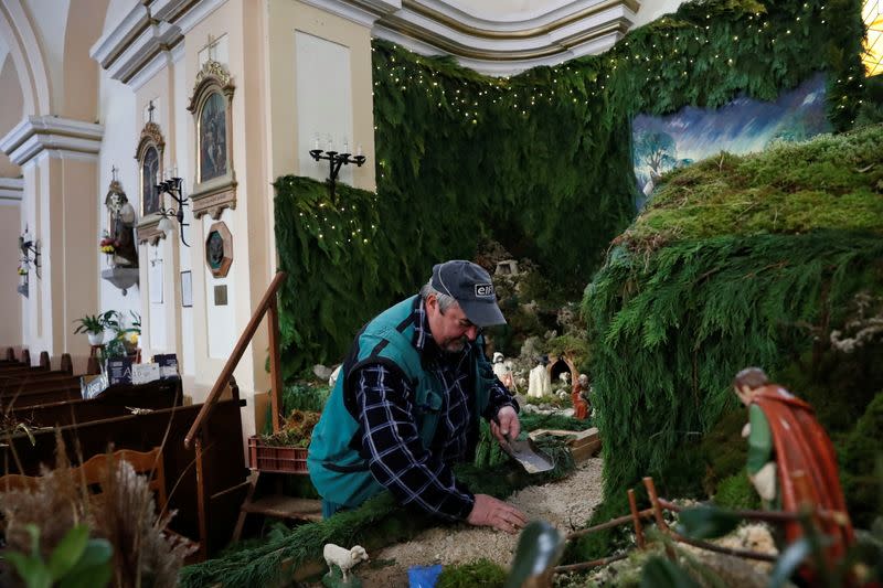 Un hombre trabaja en el montaje de un pesebre navideño en la iglesia de San Martín, Vors