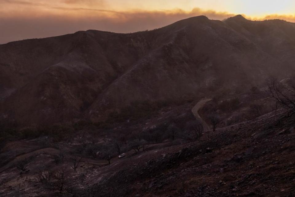 A car travels through a landscape charred by the Alisal fire on 13 October near Goleta, California.