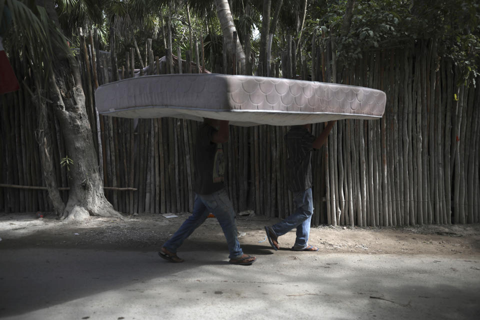 Workers carry a mattress from one hotel cabin to another in Tulum, Quintana Roo state, Mexico, Monday, Jan. 4, 2021. Tourism, which has been affected by the new coronavirus pandemic, accounts for 87% of Quintana Roo's gross domestic product, said state Tourism Secretary Marisol Vanegas. (AP Photo/Emilio Espejel)