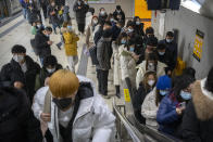 Commuters wearing face masks to protect against COVID-19 ride an escalator at a subway station in the central business district in Beijing on Dec. 23, 2021. Caseloads of omicron have remained relatively low in many countries in Asia. For now, many remain insulated from the worst, although the next few months will remain critical. (AP Photo/Mark Schiefelbein)