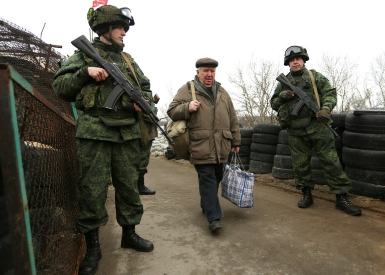 Pro-Russian rebels guard a checkpoint in Stanytsia Luhanska, Lugansk region, on March 7, 2017, as a man carrying bags passes into Ukraine-controlled territory