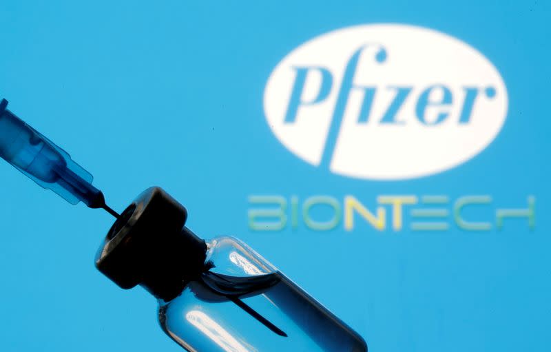 FILE PHOTO: Vial and sryinge are seen in front of displayed Pfizer and Biontech logo