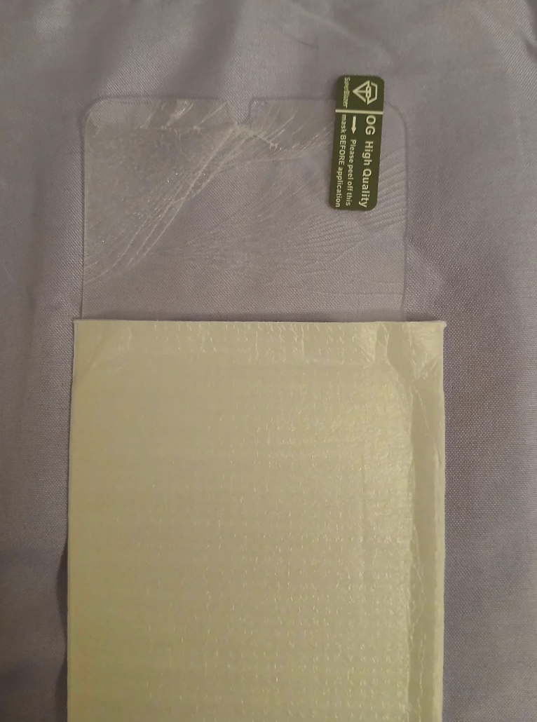 Sealed bubble envelope with a green “Go Green” sticker on top, lying on a fabric surface