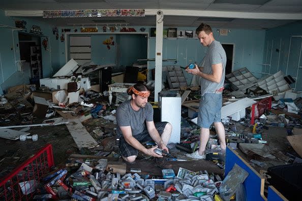 Seth Jones, left, sorts through storm damaged video games as Jason Crosser looks on at Crossers storm damaged business, 8-Bit Hall of Fame, after Hurricane Ian on September 29, 2022, in Bonita Springs, Florida.