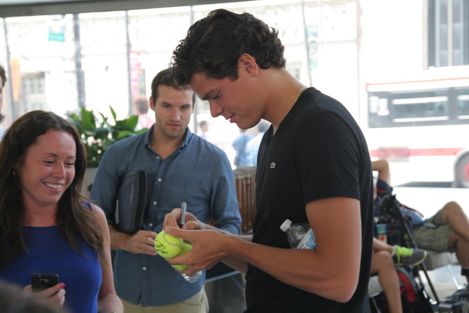 Milos Raonic signs a tennis ball for a fan at Commerce Court in Toronto. (Photo Courtesy Alex Jones Photography)