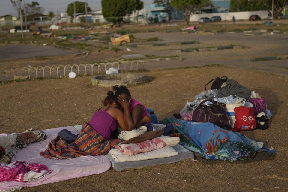 A Venezuelan migrant cries with her daughter after sleeping outdoors in the parking lot of a bus terminal in Boa Vista, Roraima state, Brazil, Friday, April 7, 2023. (AP Photo/Matias Delacroix)