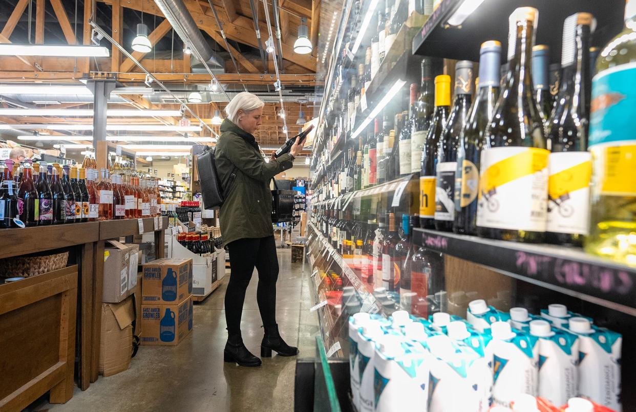 Alyssa Roberts considers the price of a bottle of wine while shopping at The Hills Market Downtown on Friday. Roberts was stocking up for the holiday weekend, as she will be hosting Thanksgiving this year for family.