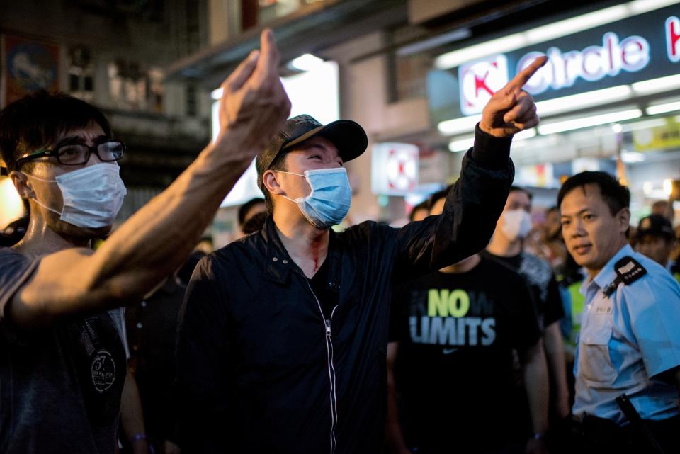 A group of men shout at pro-democracy protesters after fighting running battles as a policeman looks on in the Causeway Bay district of Hong Kong on October 3, 2014. (Alex Ogle/AFP/Getty Images)