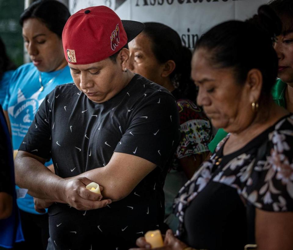 Jeremías López García, a la izquierda, con una gorra roja, hermano de Efraín López García, inclina la cabeza en señal de oración mientras líderes comunitarios, trabajadores y familiares se reúnen durante una vigilia organizada por la Farmworker Association of Florida.