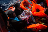 <p>Migrant women from Nigeria, one of them holding a baby, are rescued by emergency teams from a dinghy as they were sailing at the Mediterranean sea toward the Italian coasts, about 17 miles north of Sabratha, Libya, Sunday, Aug. 28, 2016. More than seven hundred migrants were rescued Sunday morning from seven boats by members of Proactiva Open Arms NGO before transferring them to the Italian cost guards operating at the zone. (AP Photo/Emilio Morenatti) </p>