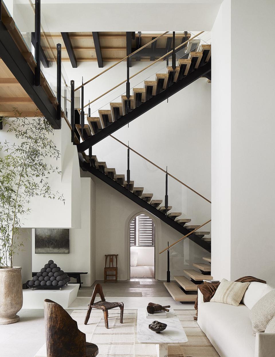 A central staircase rises several floors above a white-walled living room