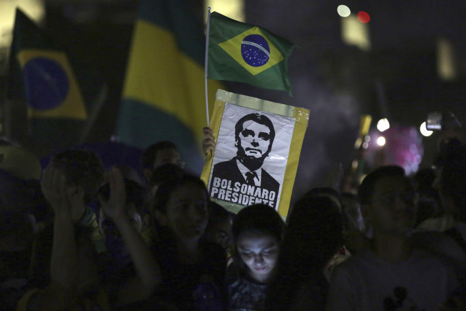 Supporters of presidential candidate Jair Bolsonaro stand outside the National Congress where they gathered to celebrate his presidential victory, in Brasilia, Brazil, Sunday, Oct. 28, 2018. Brazil's Supreme Electoral Tribunal declared the far-right congressman the next president of Latin America's biggest country. (AP Photo/Eraldo Peres)