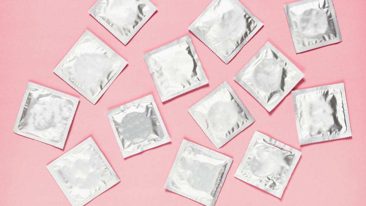 silver wrapped condoms on pink background