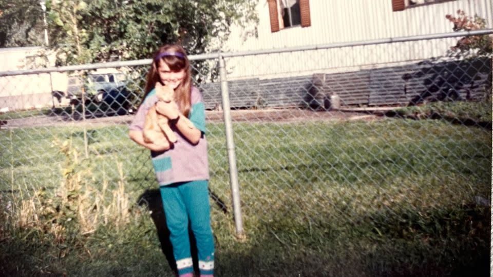 Carrie Sheffield with the family cat Buff, approximately age 11 in fifth grade in the family backyard of their Springville, Utah mobile home park. - Courtesy Carrie Sheffield