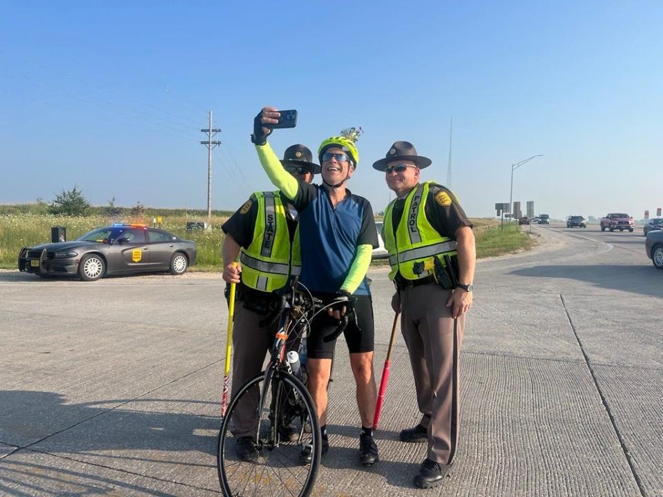 A biker from Israel stops on his way from Storm Lake to Early to snap a selfie with State Troopers Bob Conrad and Kevin Krull on Monday.