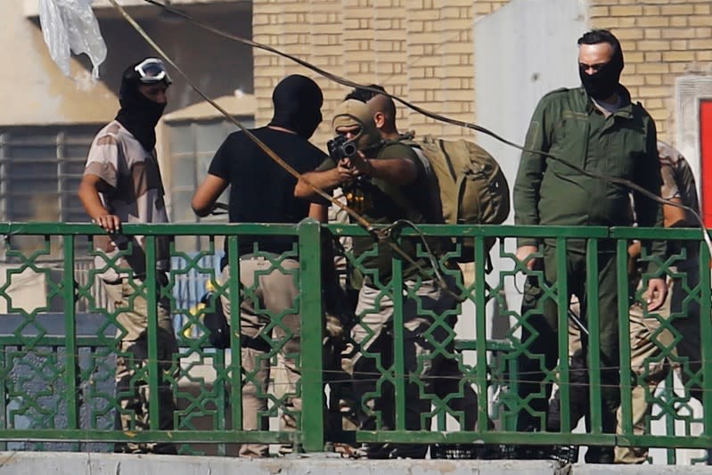 A member of Iraqi security forces points his gun towards the demonstrators during the ongoing anti-government protests in Baghdad