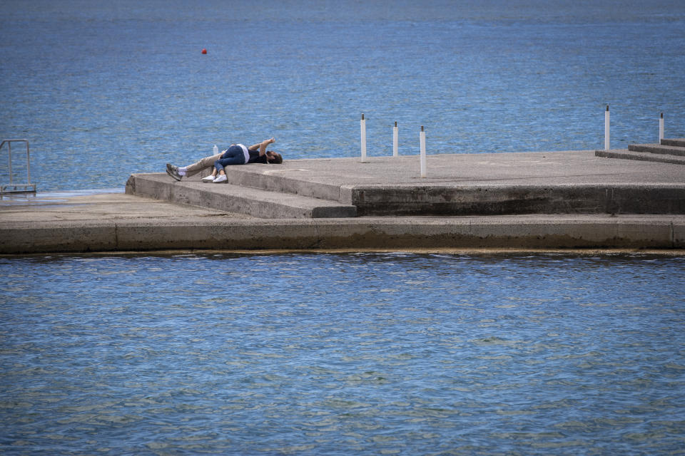 A couple lays at the seafront in Opatija, Croatia, Saturday, May 15, 2021. Croatia has opened its stunning Adriatic coastline for foreign tourists after a year of depressing coronavirus lockdowns and restrictions. (AP Photo/Darko Bandic)