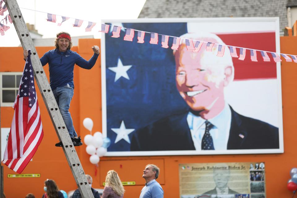 A man puts a U.S. flag up in the town of Ballina, the ancestral home of President-elect Joe Biden, in North West of Ireland, on Nov. 7, 2020, after Biden was elected president.