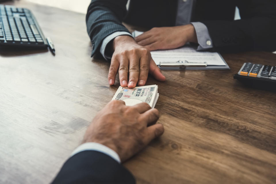 A hand passing money across a table.