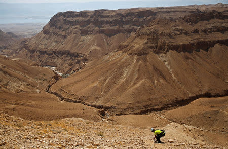 A volunteer with the Israeli Antique Authority holds a securing rope as he walks down to enter the Cave of the Skulls, an excavation site in the Judean Desert near the Dead Sea, Israel. REUTERS/Ronen Zvulun