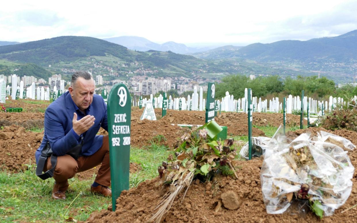 A man visits the graves of his parents in law, who died of Covid-19 complications, in Zenica, Bosnia - Almir Alic /AP