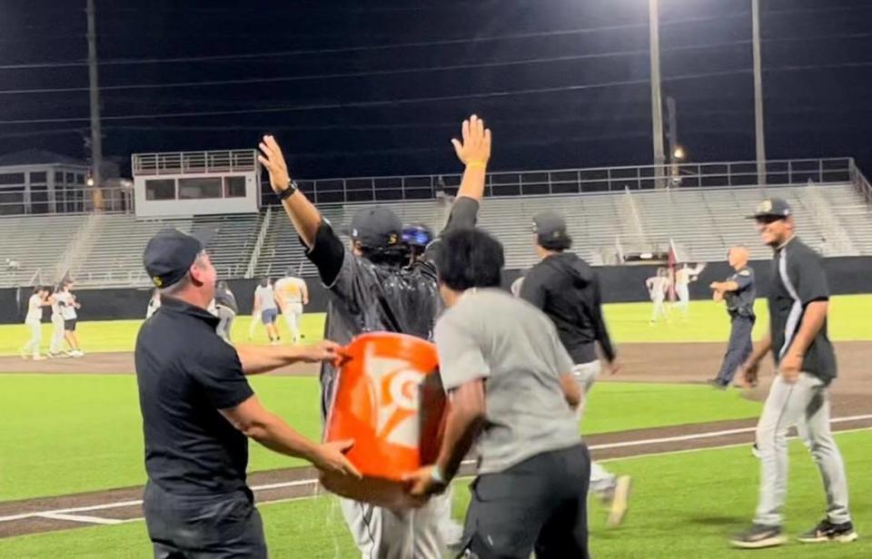 Sunset baseball coach Julio Mendoza (arms raised) is doused with water and ice by his assistant coaches after the Knights upset Key West 2-1 in the Region 4-4A final on Tuesday night.