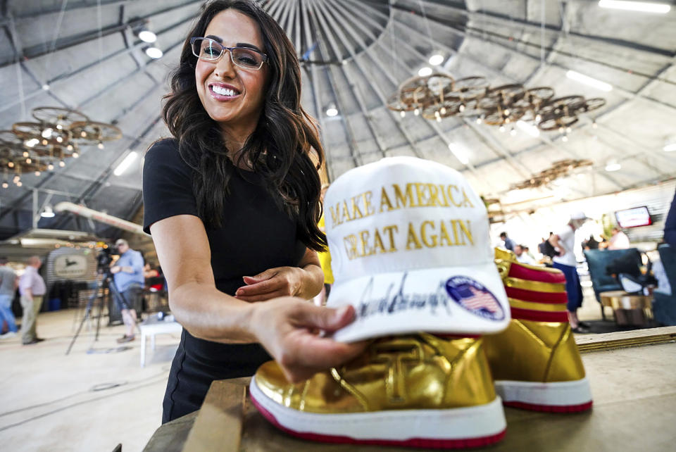 Rep. Lauren Boebert, R-Colo., arranges a Make America Great Again hat and a pair of gold Converse All-Stars basketball shoes on the stage at her primary election watch party Tuesday, June 25, 2024, in Windsor, Colo. (Hart Van Denburg/Colorado Public Radio via AP)