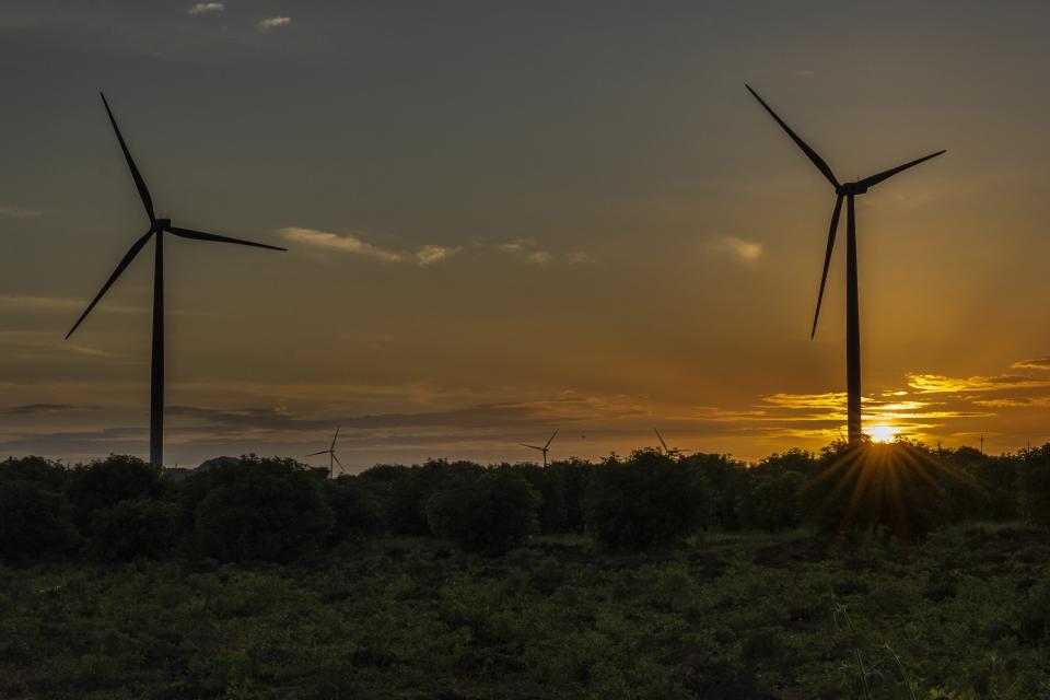 The sun sets behind a wind turbines in Anantapur district, Andhra Pradesh, India, Wednesday, Sept 14, 2022. Over 500 energy industry heavyweights will descend on the southern Indian city of Bengaluru on Monday, Feb. 6, 2023, to discuss the future of renewables and fossil fuels at India Energy Week — the first big ticket event of the country's presidency of Group of 20 leading economies. (AP Photo/Rafiq Maqbool)