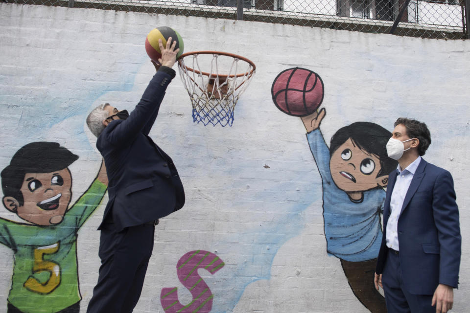 Mayor of London Sadiq Khan, left, jumps for the basket, joined by Labour Party shadow business secretary Ed Miliband at the Play, Adventure & Community Engagement Fairfield Play Centre in London, Tuesday April 6, 2021. Khan and Miliband met with staff and children as they take part in hands-on, environmentally-friendly activities following launching Khan's election manifesto ahead of the London Mayoral election. (Stefan Rousseau/PA via AP)