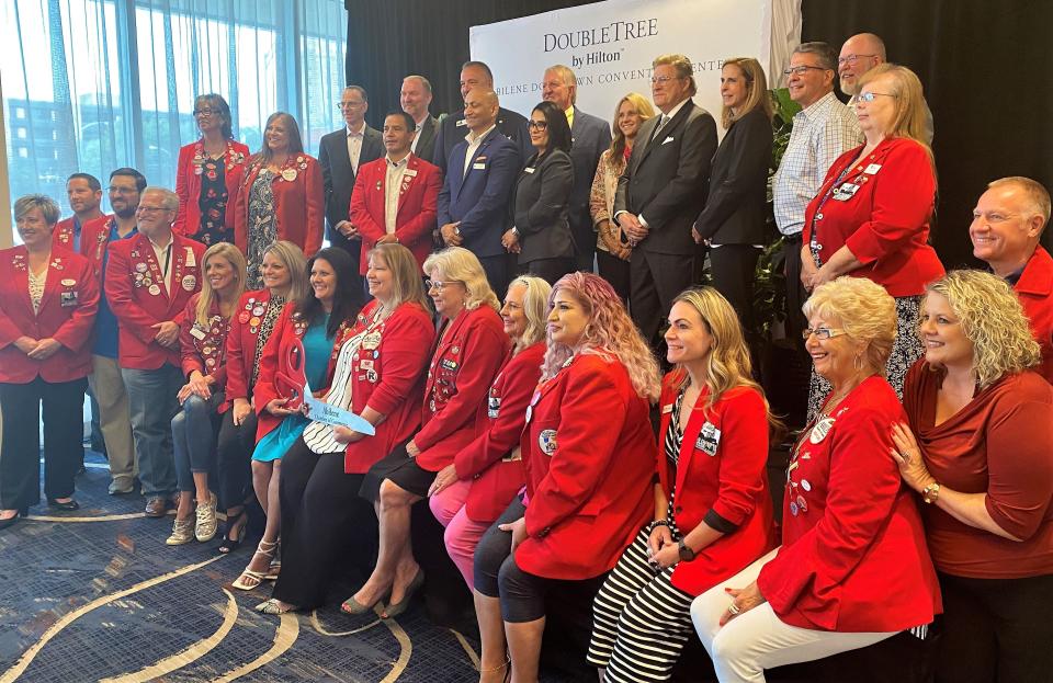 Guests including state Sen. Charles Perry, third from right, standing, pose for photos with Abilene Chamber of Commerce Redcoats before a ribbon is cut Tuesday to officially open the DoubleTree by Hilton in downtown Abilene.
