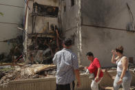 People look at a residential building after it was hit by a rocket fired from the Gaza Strip, in Ashdod, Israel, Monday, May 17, 2021. (AP Photo/Maya Alleruzzo)