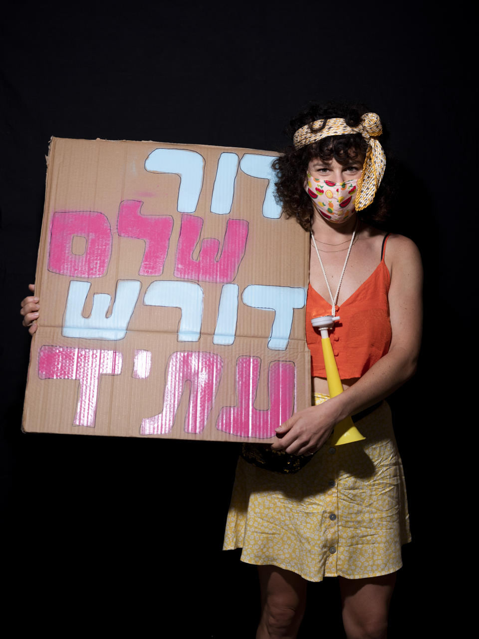 Kalanit Sharon, 31, poses for a photo during a protest against Israel's Prime Minister Benjamin Netanyahu, outside his residence in Jerusalem, Thursday, July 23, 2020. Hebrew on sign reads "An entire generation demands for future". The wave of colorful and combative demonstrations against Netanyahu and his perceived failure to handle the country's deepening economic crisis have been characterized by youth. With flags, facemasks, drums, placards and an assortment of props, thousands have been taking to the streets to demand change in a variety of unique ways. (AP Photo/Oded Balilty)