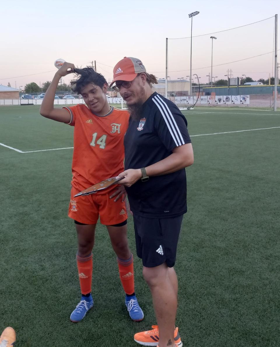 Damian Lopez (left) listens to instructions from Artesia High School head soccer coach Phillip Jowers.