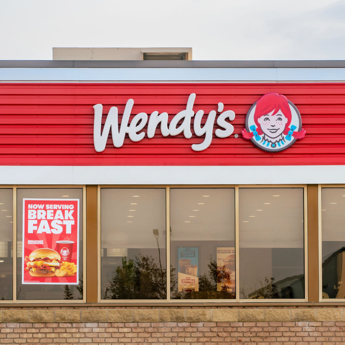 Wendy's restaurant exterior with 'Now Serving Breakfast' sign in window