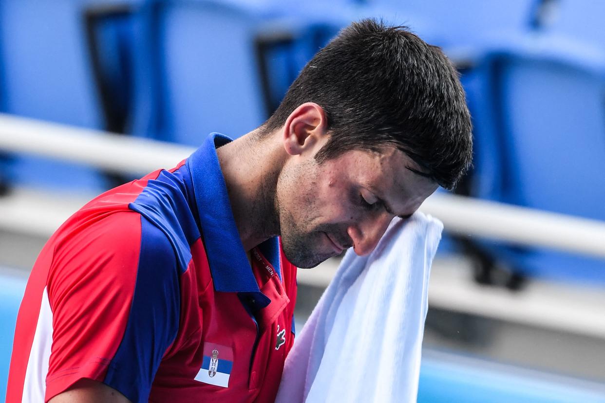 Serbia's Novak Djokovic wipes his face during his Tokyo 2020 Olympic Games men's singles tennis match for the bronze medal against Spain's Pablo Carreno Busta at the Ariake Tennis Park in Tokyo on July 31, 2021. (Photo by Tiziana FABI / AFP) (Photo by TIZIANA FABI/AFP via Getty Images)