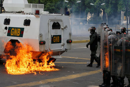 Riot police officers stand near flames from molotov cocktails thrown at a water cannon by opposition supporters during a rally against Venezuela's President Nicolas Maduro in Caracas, Venezuela, April 26, 2017. REUTERS/Carlos Garcia Rawlins