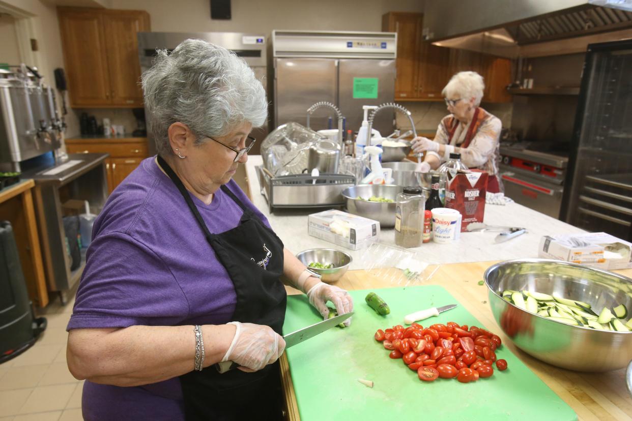 Volunteers Jennider Smith, left, and Bev Fry work to prepare a meal for Compassion Delivered Inc. at Evermore Community Church in Hartville.
