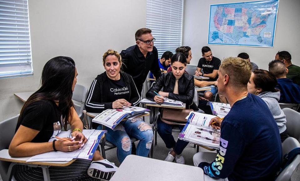 El profesor de inglés Enrique Avila (de pie) repasa algunos ejercicios de oratoria con estudiantes (en su mayoría cubanos), recién llegados a Miami y que estudian inglés en el edificio del Miami Dade College REVEST Program en Hialeah, el jueves 16 de marzo de 2023.