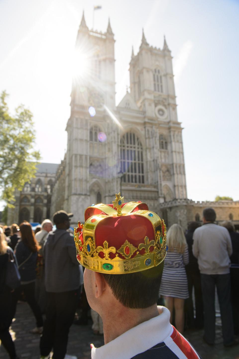 A man wearing a crown waits outside Westminster Abbey (PA)