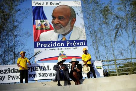 Haitians chat as they wait for the start of the funeral for Haiti's former President Rene Preval in Port-au-Prince, Haiti, March 11, 2017. The poster reads in creole, "Thank you Little Rene. President Preval". REUTERS/Andres Martinez Casares