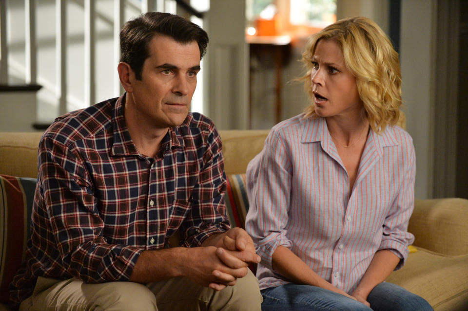 Ty Burrell and Julie Bowen, as Phil and Claire Dunphy, sit on a couch looking surprised in a scene from the TV show 'Modern Family'