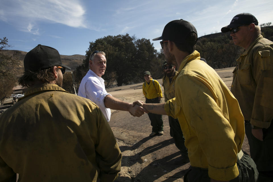 U.S. Secretary of the Interior Ryan Zinke, second from left, shakes hands with firefighters while visiting decimated Paramount Ranch Thursday, Nov. 15, 2018, in Agoura Hills, Calif. The landmark film location burned to the ground by the Woolsey Fire. (AP Photo/Jae C. Hong)