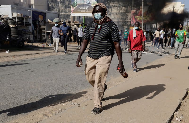 Senegalese demonstrators hold stones during clashes with riot police as they protest against the postponement of the Feb. 25 presidential election, in Dakar