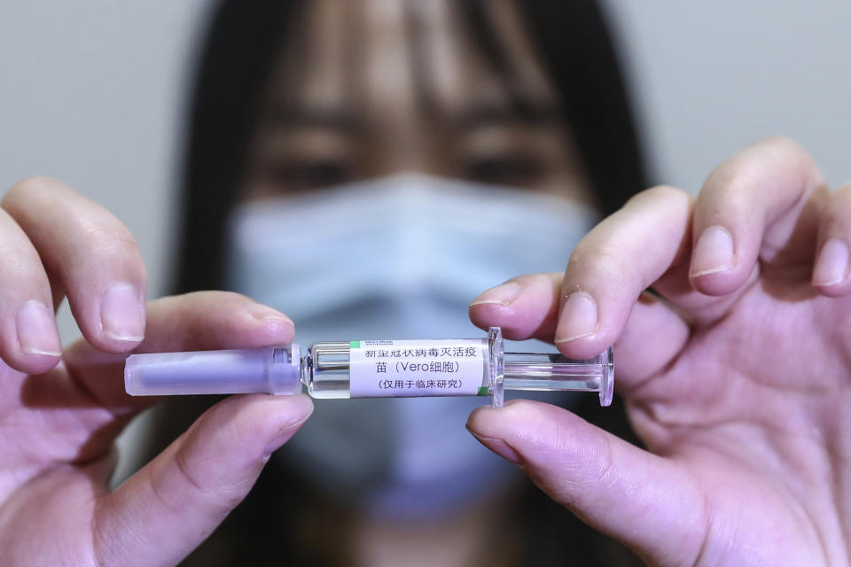 In this April 10, 2020, photo released by Xinhua News Agency, a staff member holds up a sample of a potential COVID-19 vaccine at a production plant of SinoPharm in Beijing. In the global race to make a coronavirus vaccine, the state-owned Chinese company is boasting that it gave its employees, including top executives, experimental shots even before the government OK'd testing in people. (Zhang Yuwei/Xinhua via AP)