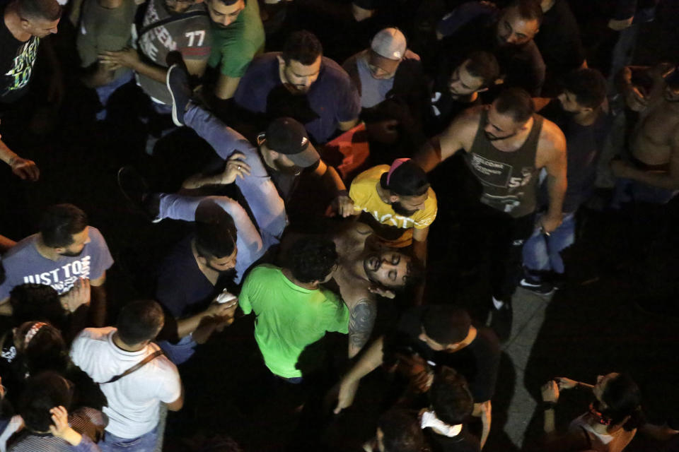 Anti-government protesters help a man who was injured during clashes with riot policemen in Beirut, Lebanon, Friday, Oct. 18, 2019. Lebanon erupted in protests Thursday over the government's plans to impose new taxes amid a severe economic crisis, taking their anger on politicians they accuse of widespread corruption and decades of mismanagement. (AP Photo/Hassan Ammar)