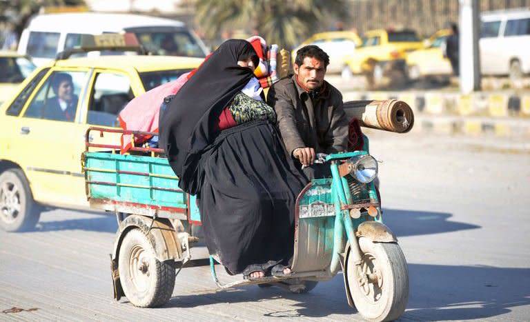 A Syrian woman is driven on a three wheeler auto in Aleppo's old city on January 17, 2013