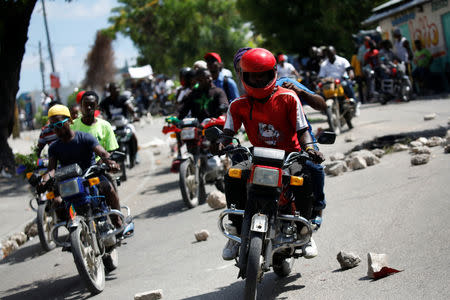 Protesters ride their motorbikes along a street blocked by rocks during a march to demand an investigation into what they say is the alleged misuse of Venezuela-sponsored PetroCaribe funds, in Port-au-Prince, Haiti, October 17, 2018. REUTERS/Andres Martinez Casares