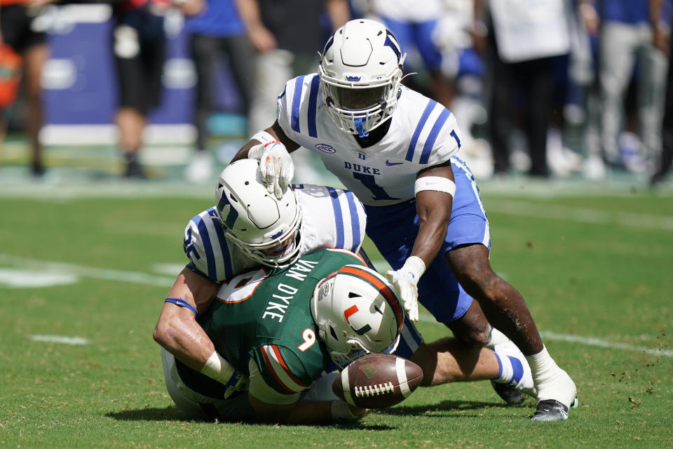 Miami quarterback Tyler Van Dyke (9) fumbles the ball as he is taken down by Duke linebacker Cam Dillon and defensive back Darius Joiner (1) during the first half of an NCAA college football game, Saturday, Oct. 22, 2022, in Miami Gardens, Fla. (AP Photo/Wilfredo Lee)