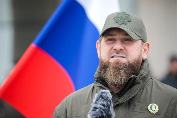 Chechen leader Ramzan Kadyrov at a microphone in front of a Russian flag.